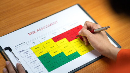 Wall Mural - action of a person is using ballpoint pen to marking on the risk assessment matrix table at 
