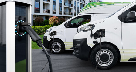 Sticker - Electric vehicles charging station on a background of delivery vans. Concept	