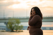 © Юля Бурмистрова - Curly black-haired cute smiling and joyful plump Afro-American, multiracial woman against sea, river on summer beach vacation. Multiracial female. Love yourself, body positive, acceptance. Copy space