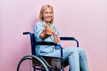 Sticker - Beautiful blonde woman sitting on wheelchair beckoning come here gesture with hand inviting welcoming happy and smiling