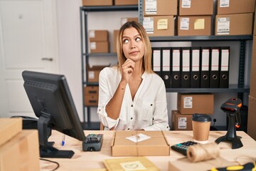 Canvas Print - Young blonde woman working at small business ecommerce with hand on chin thinking about question, pensive expression. smiling with thoughtful face. doubt concept.