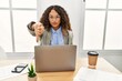 © Krakenimages.com - Beautiful hispanic business woman sitting on desk at office working with laptop looking unhappy and angry showing rejection and negative with thumbs down gesture. bad expression.