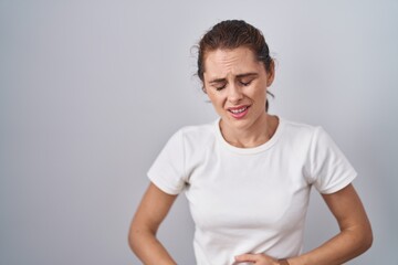 Sticker - Beautiful brunette woman standing over isolated background with hand on stomach because indigestion, painful illness feeling unwell. ache concept.