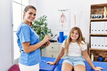 Canvas Print - Woman and girl physiotherapist and patient having rehab session at physiotherapy clinic