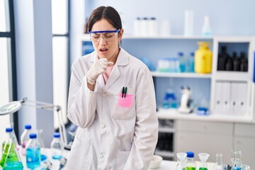 Poster - Young brunette woman working at scientist laboratory feeling unwell and coughing as symptom for cold or bronchitis. health care concept.