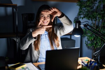 Canvas Print - Young brunette woman working at the office at night smiling making frame with hands and fingers with happy face. creativity and photography concept.