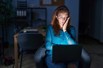 Sticker - Brunette woman working at the office at night thinking looking tired and bored with depression problems with crossed arms.