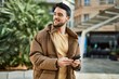 © Krakenimages.com - Young hispanic man smiling happy using smartphone at the city.