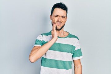 Canvas Print - Young hispanic man wearing casual clothes touching mouth with hand with painful expression because of toothache or dental illness on teeth. dentist