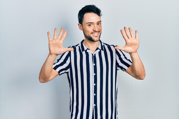 Poster - Young hispanic man wearing casual clothes showing and pointing up with fingers number ten while smiling confident and happy.