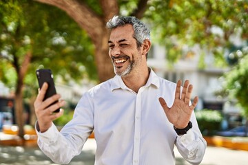 Sticker - Middle age grey-haired man doing video call using smartphone at the city.