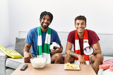 Poster - Young hispanic brothers football hooligans holding ball and megaphone looking positive and happy standing and smiling with a confident smile showing teeth