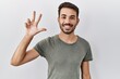 © Krakenimages.com - Young hispanic man with beard wearing casual t shirt over white background showing and pointing up with fingers number three while smiling confident and happy.