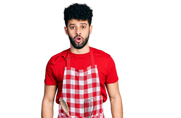 Canvas Print - Young arab man with beard wearing cook apron afraid and shocked with surprise expression, fear and excited face.