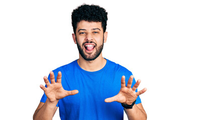 Sticker - Young arab man with beard wearing casual blue t shirt smiling funny doing claw gesture as cat, aggressive and sexy expression