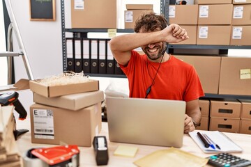 Poster - Young hispanic call center agent man working at warehouse smiling cheerful playing peek a boo with hands showing face. surprised and exited