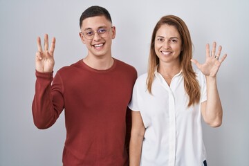 Poster - Mother and son standing together over isolated background showing and pointing up with fingers number eight while smiling confident and happy.