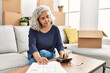Middle age grey-haired woman sitting on the sofa calculate savings at new home.