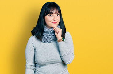 Poster - Young hispanic plus size woman wearing winter scarf looking confident at the camera smiling with crossed arms and hand raised on chin. thinking positive.