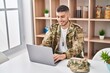 © Krakenimages.com - Young hispanic man army soldier using laptop sitting on table at home