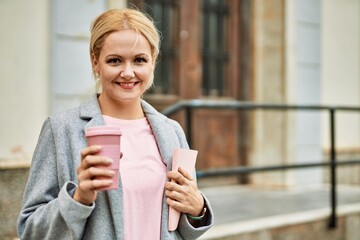 Canvas Print - Young blonde businesswoman smiling happy drinking coffee at the city.