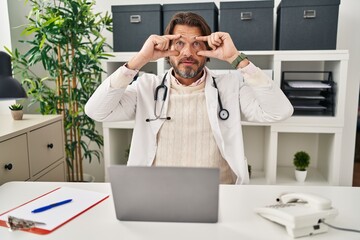 Sticker - Handsome middle age doctor man working at the clinic trying to open eyes with fingers, sleepy and tired for morning fatigue