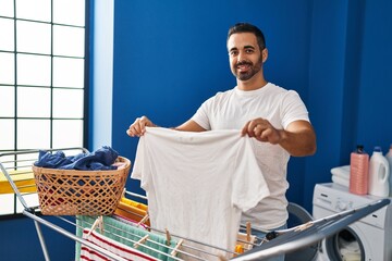 Canvas Print - Young hispanic man smiling confident hanging clothes on clothesline at laundry room