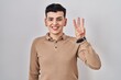 Non binary person standing over isolated background showing and pointing up with fingers number three while smiling confident and happy.