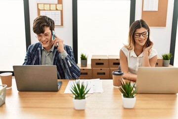 Wall Mural - Two business workers smiling happy working using smartphone and laptop at the office.