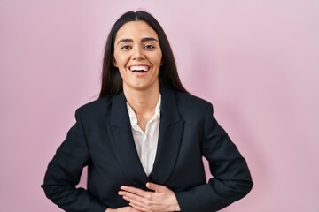 Wall Mural - Young brunette woman wearing business style over pink background smiling and laughing hard out loud because funny crazy joke with hands on body.