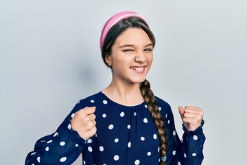 Wall Mural - Young brunette girl wearing elegant look excited for success with arms raised and eyes closed celebrating victory smiling. winner concept.