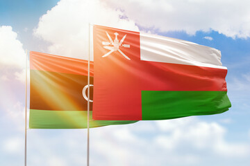 Sunny blue sky and flags of oman and libya