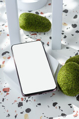 Canvas Print - mobile phone on white geometric pedestal on terrazzo background with summer sunlight and moss rock