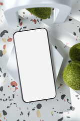 Poster - mobile phone on white geometric pedestal on terrazzo background with summer sunlight and moss rock