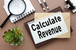 © Svetlana - calendar, plant, pen and white notebook with text CALCULATE REVENUE