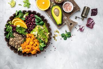 Quinoa salad in bowl with avocado, sweet potato, beans on gray background. superfood concept. Healthy, clean eating concept. Vegan or gluten free diet. top view