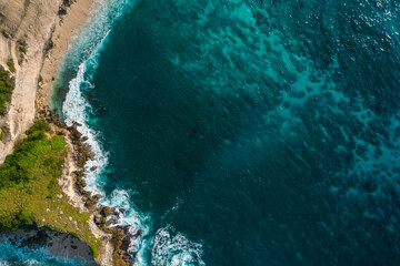 Poster - Aerial drone top view shot of rocky beach with cliff. Indian ocean shore. Copy space for text. Nature and travel background. Beautiful natural summer vacation travel concept. Waves and sand.