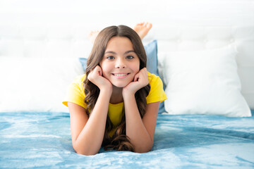 Wall Mural - Teenager child girl resting in bed at home bedroom. Kid relaxing in bedroom interior. Kid daydreaming, dreaming.