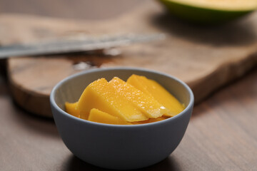 Wall Mural - Fresh sliced mango in a ceramic bowl on walnut table