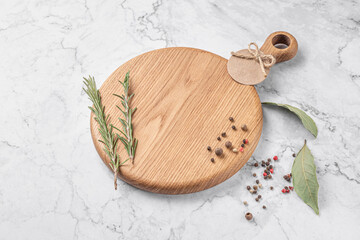 Wall Mural - round wooden cutting board with a handle. thyme and spices on a white marble background. mockup with copy space for text, side view