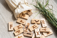 RANDOM WOODEN RUNES WITH SYMBOLS IN A DRY Healing Herb For Fortune Telling And Fortune Telling Are Scattered On A LIGHT NATURAL Cotton FABRIC Made Of A Linen Bag With A Rope