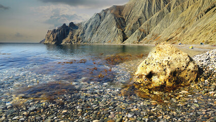 Wall Mural - Sea pebbles, filmed on the Crimean Peninsula, Eastern Crimea, near Feodosia, The Karadag mountain range is visible in the distance. 