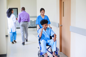 Wall Mural - young nurse pushing young black man patient on a wheelchair in the hospital corridor to the patient room