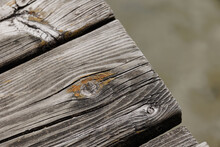 Old Wooden Planks With Knotholes Of A Pier Over Lake Water