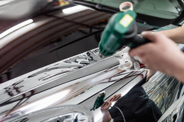 Wall Mural - Car wrapping specialist putting silver mirror chrome foil on car. Selective focus.