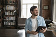 © fizkes - Smiling business man use accounting and finances or management apps on digital tablet standing alone in home office staring aside feels satisfied, comfort, easy work use modern tech, workflow concept