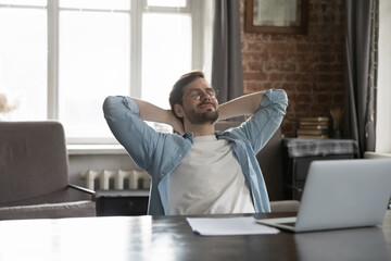 Satisfied by work done employee put hands behind head breath fresh-conditioned air looks carefree sit at workplace desk with laptop enjoy comfort break, relax alone in modern office. No stress concept