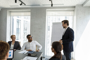 Poster - Group of multi ethnic people take part in meeting or negotiations led by businessman in suit standing in front of businesspeople make speech, gives presentation on flip chart. Training event concept