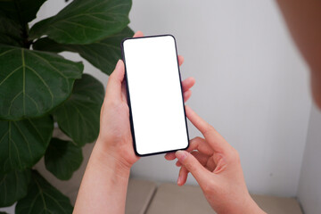 Mockup picture of business woman’s hands holding smart phone with white blank screen in modern place