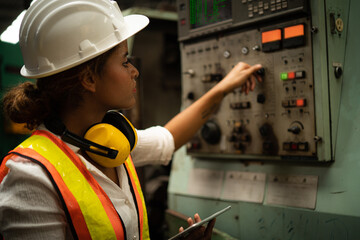 Portrait from behind of industrial worker woman working with industrial machine in factory site, Industry occupation concept.